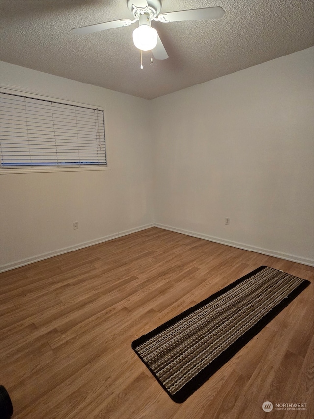 empty room featuring hardwood / wood-style flooring, ceiling fan, and a textured ceiling