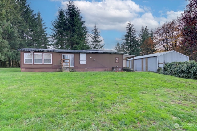 back of property with a garage, an outbuilding, and a yard