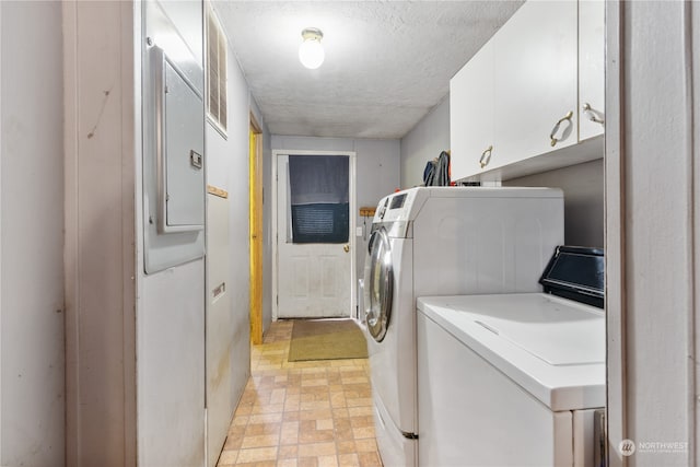 laundry area with a textured ceiling, electric panel, cabinets, and washer and dryer