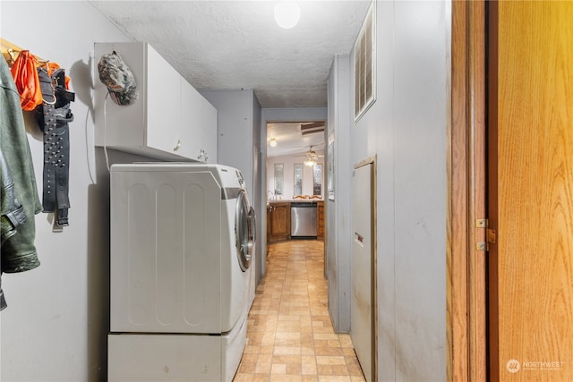 laundry room with a textured ceiling, washing machine and dryer, cabinets, and ceiling fan