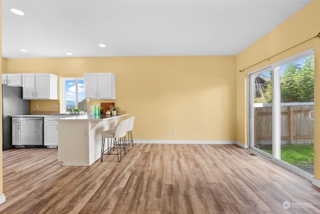 404 E 31st St, Bremerton, WA 98310 - kitchen with white cabinets, a kitchen bar, light hardwood / wood-style flooring, and stainless steel dishwasher