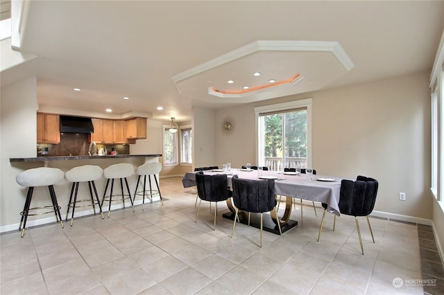 tiled dining room with a tray ceiling and a wealth of natural light