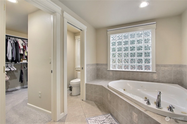 bathroom with tile patterned floors, plenty of natural light, toilet, and tiled tub