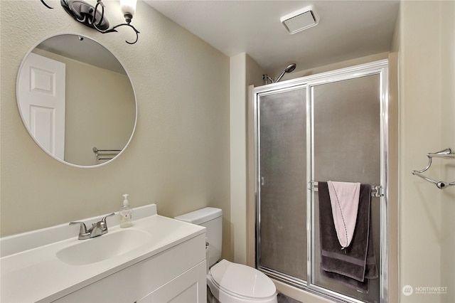 bathroom with vanity, toilet, and a shower with shower door