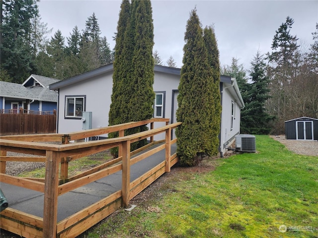 view of home's exterior with a shed, a deck, a yard, and central AC