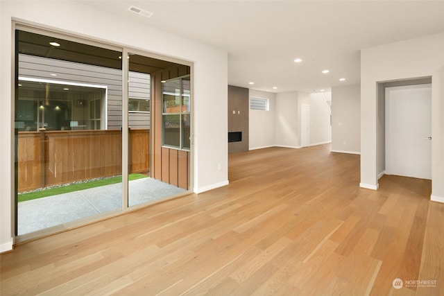 empty room with a tile fireplace and light hardwood / wood-style flooring