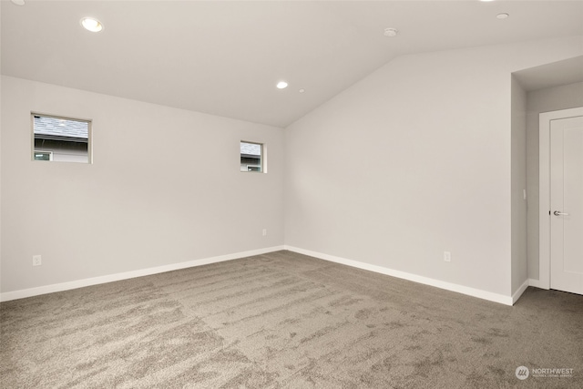 unfurnished room featuring a healthy amount of sunlight, carpet floors, and vaulted ceiling