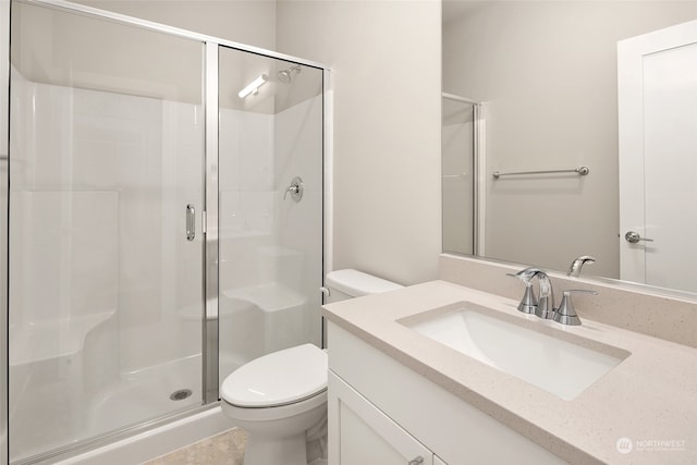 bathroom featuring a shower with shower door, toilet, and vanity