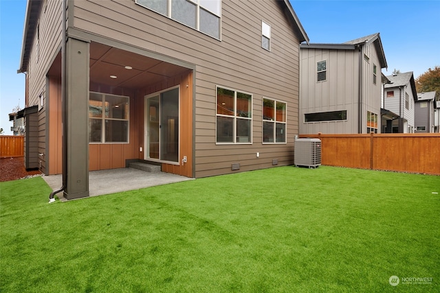 rear view of property with cooling unit, a patio area, and a yard