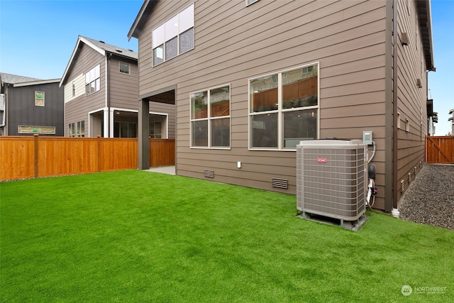 rear view of property with a lawn and central AC