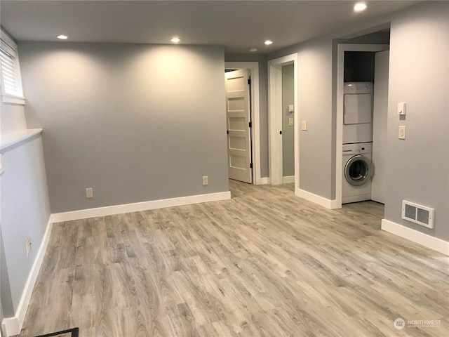 clothes washing area featuring light hardwood / wood-style floors and stacked washer / drying machine