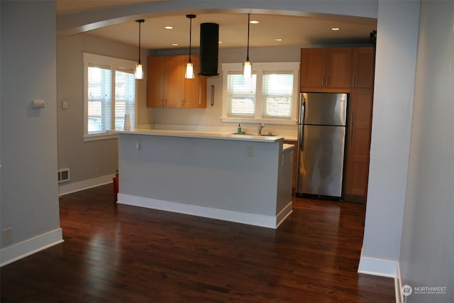 kitchen with a wealth of natural light, hanging light fixtures, stainless steel fridge, and dark hardwood / wood-style floors