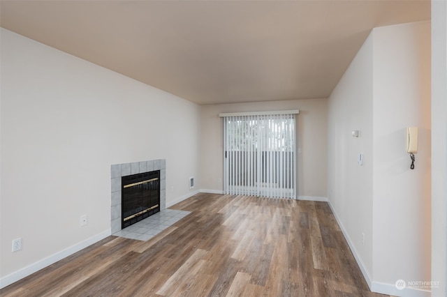 unfurnished living room with a tiled fireplace and light wood-type flooring