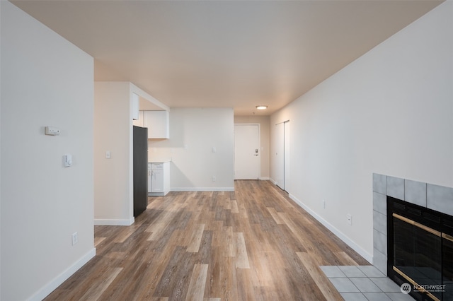 unfurnished living room featuring a tiled fireplace and light hardwood / wood-style flooring