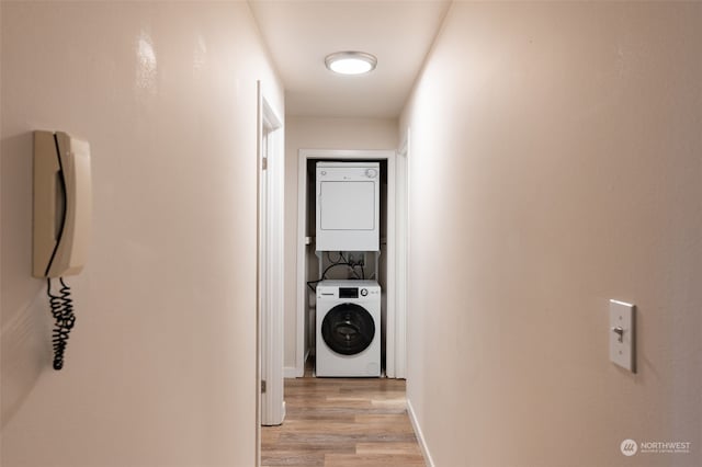 corridor featuring stacked washing maching and dryer and light hardwood / wood-style flooring