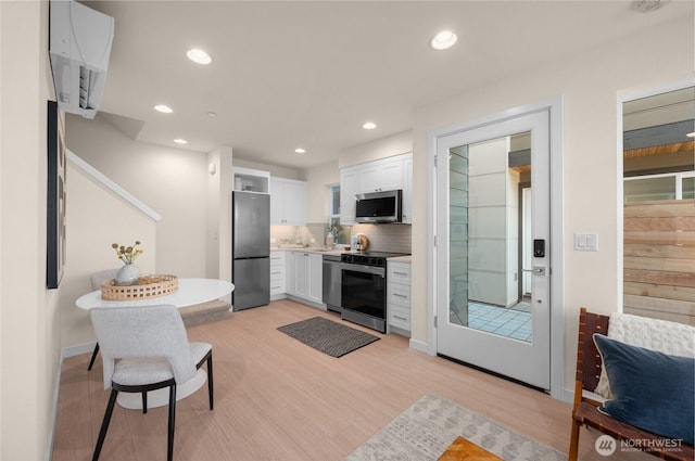 9211C Densmore Ave N, Seattle, WA 98103 - kitchen featuring appliances with stainless steel finishes, white cabinets, tasteful backsplash, light wood-style flooring, and recessed lighting