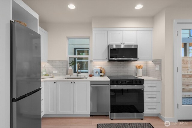 9211C Densmore Ave N, Seattle, WA 98103 - kitchen with appliances with stainless steel finishes, light countertops, white cabinetry, decorative backsplash, and recessed lighting