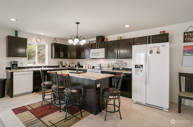 kitchen featuring sink, an island with sink, white appliances, a breakfast bar area, and decorative light fixtures