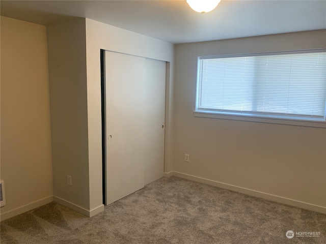 unfurnished bedroom featuring light colored carpet and a closet