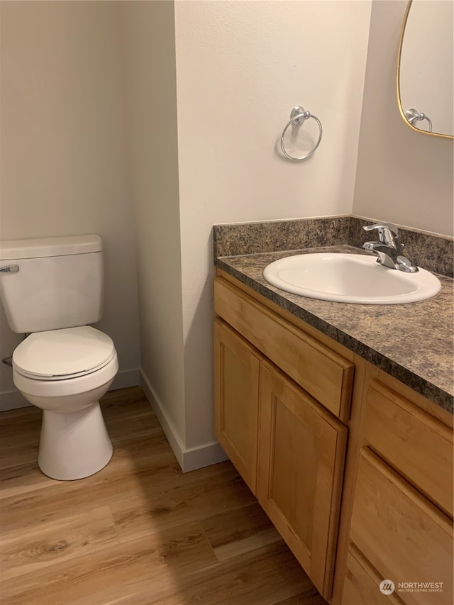 bathroom featuring toilet, vanity, and hardwood / wood-style flooring