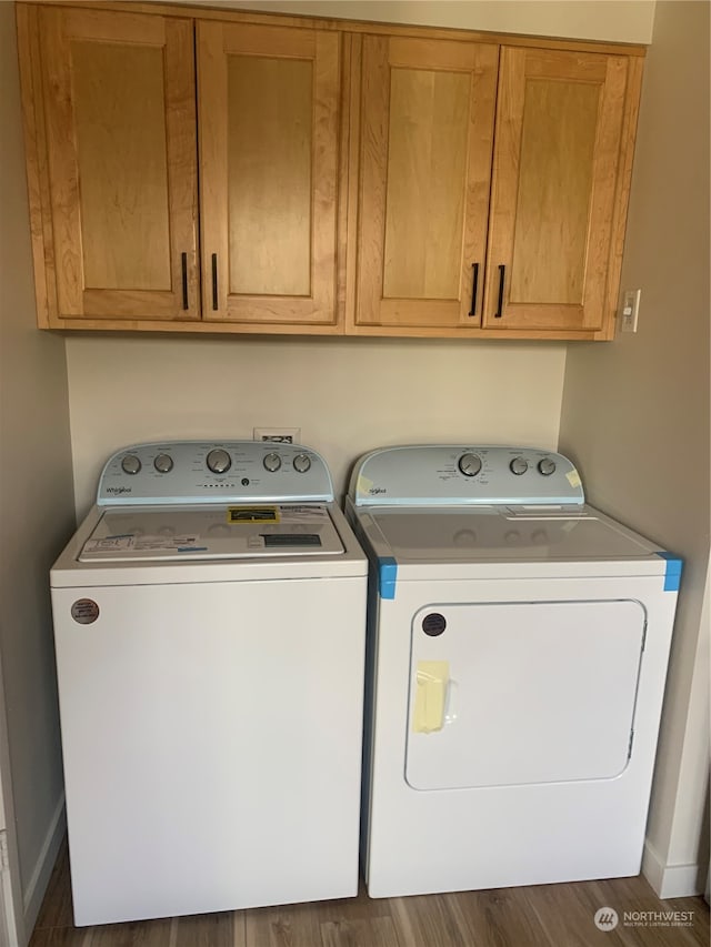 clothes washing area with dark wood-type flooring, cabinets, and independent washer and dryer