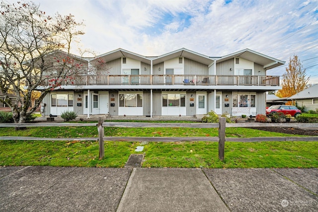 view of front of home with a balcony and a front yard