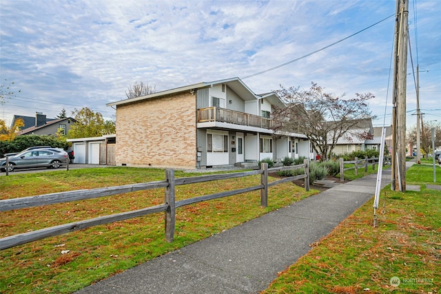 exterior space with a garage, a front lawn, and a balcony