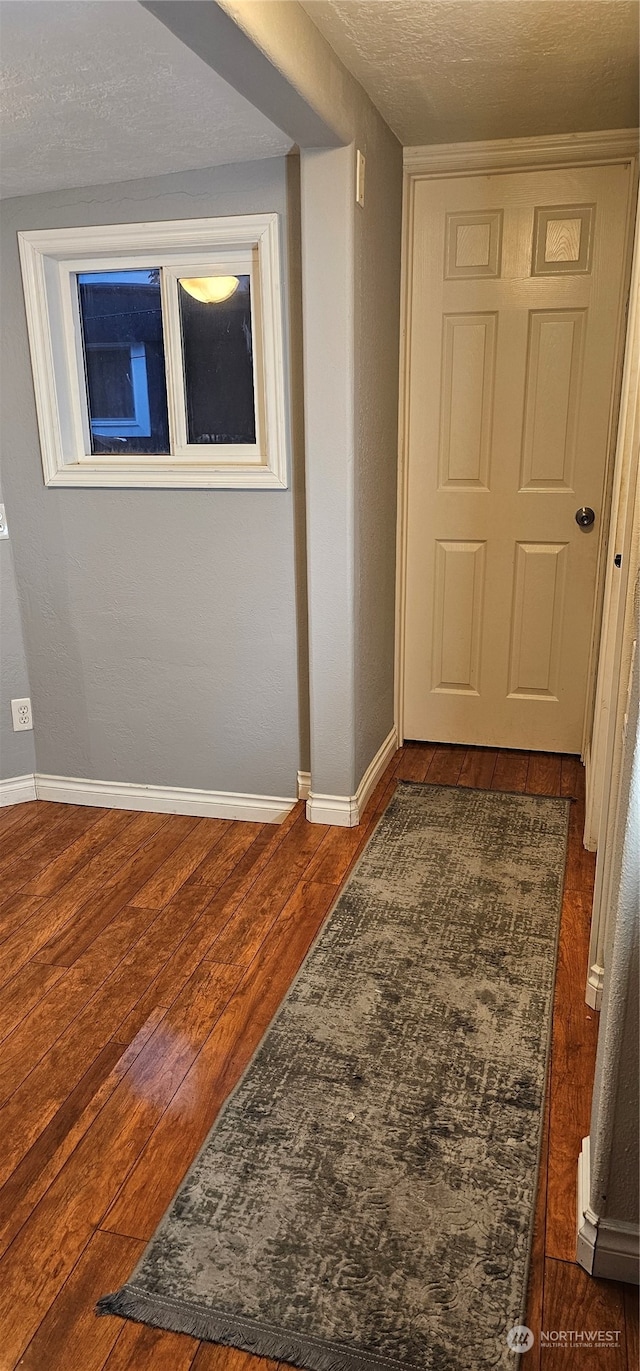 corridor featuring dark wood-type flooring and a textured ceiling