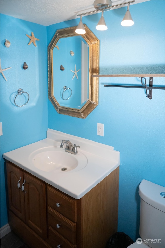 bathroom featuring vanity, a textured ceiling, and toilet