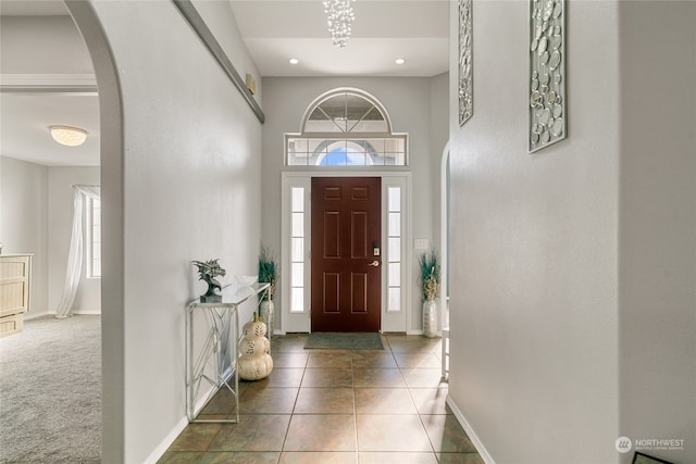 foyer entrance featuring a towering ceiling and dark tile patterned flooring