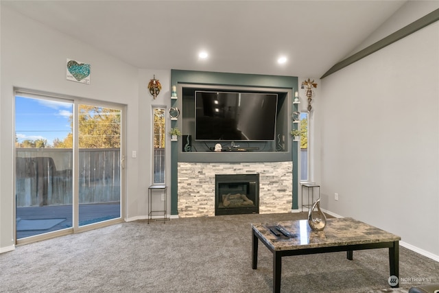 carpeted living room featuring a stone fireplace and lofted ceiling