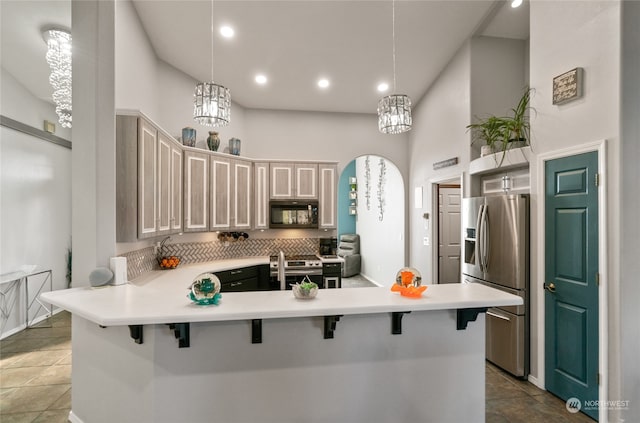 kitchen with a kitchen bar, kitchen peninsula, appliances with stainless steel finishes, and pendant lighting