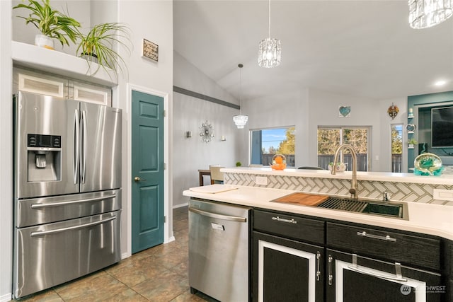 kitchen featuring lofted ceiling, sink, tasteful backsplash, appliances with stainless steel finishes, and decorative light fixtures