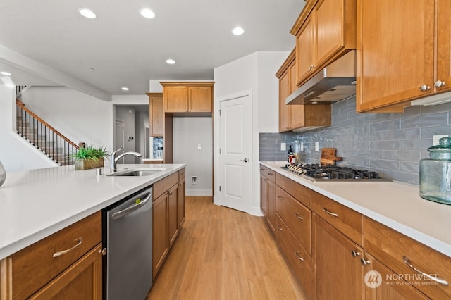 kitchen with decorative backsplash, light wood-type flooring, sink, and appliances with stainless steel finishes