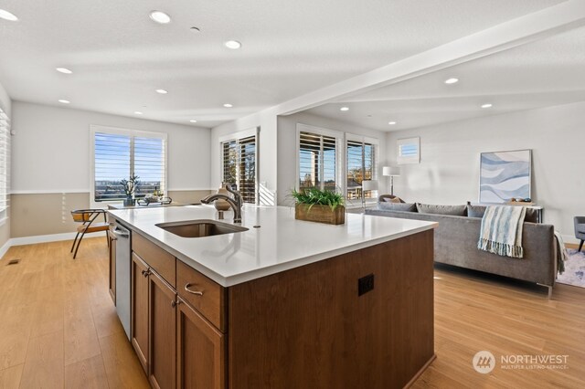 kitchen with a kitchen island with sink, sink, dishwasher, and light hardwood / wood-style floors