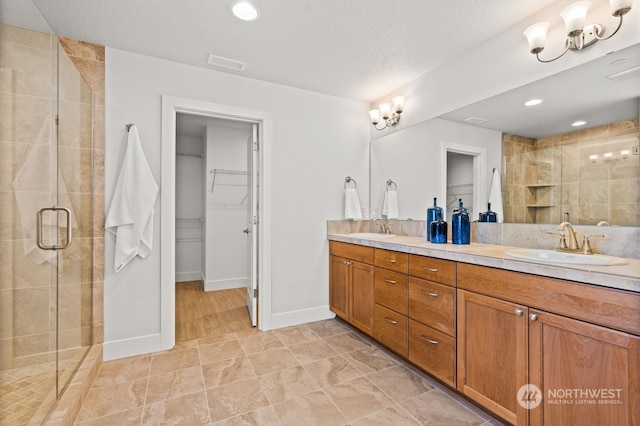 bathroom with vanity, a textured ceiling, tile patterned floors, and a shower with shower door