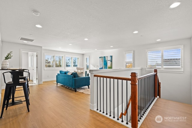 corridor featuring a textured ceiling and light hardwood / wood-style flooring