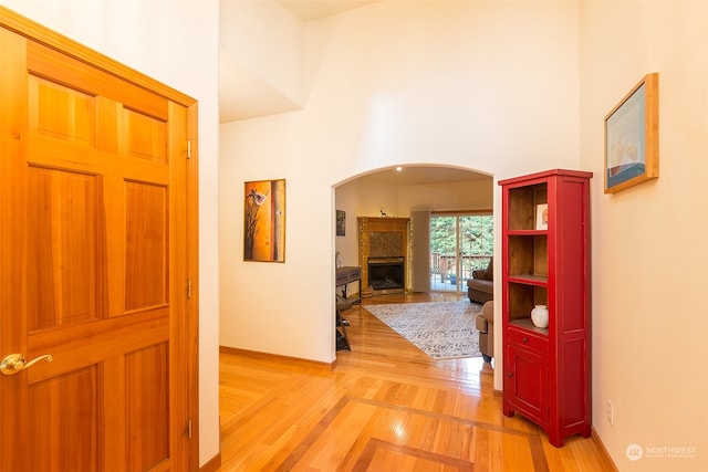 hall featuring a towering ceiling and light wood-type flooring