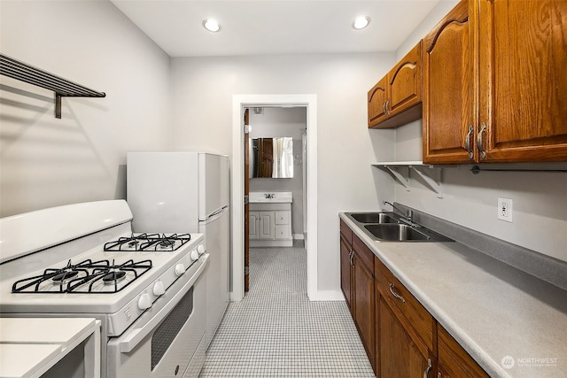 kitchen featuring white range with gas cooktop, sink, and light tile patterned floors