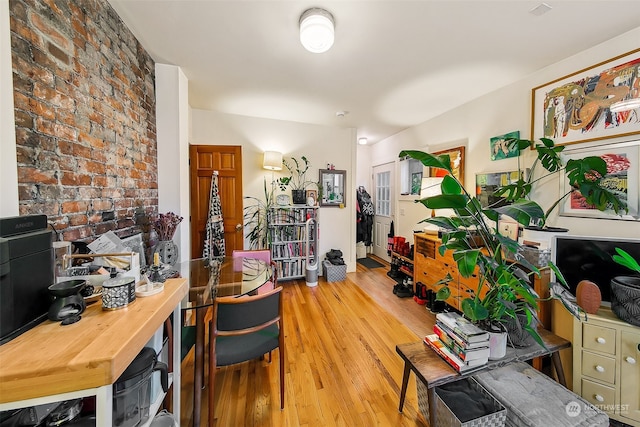 interior space with brick wall and light hardwood / wood-style flooring