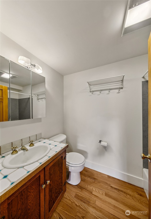 bathroom featuring wood-type flooring, toilet, vanity, and a shower