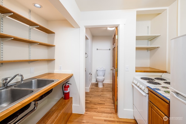 kitchen featuring light wood-type flooring, white appliances, and sink