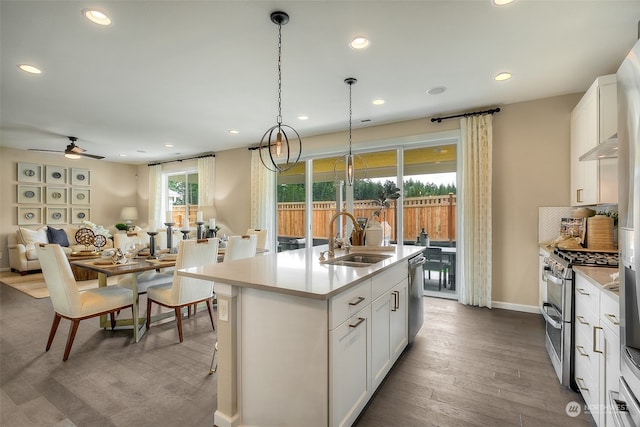 kitchen featuring white cabinetry, sink, stainless steel appliances, hardwood / wood-style floors, and a center island with sink