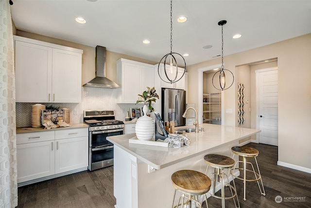 kitchen with dark hardwood / wood-style flooring, wall chimney exhaust hood, stainless steel appliances, a center island with sink, and white cabinetry