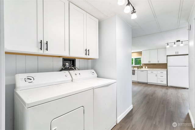 washroom featuring cabinets, hardwood / wood-style floors, track lighting, and washer and clothes dryer