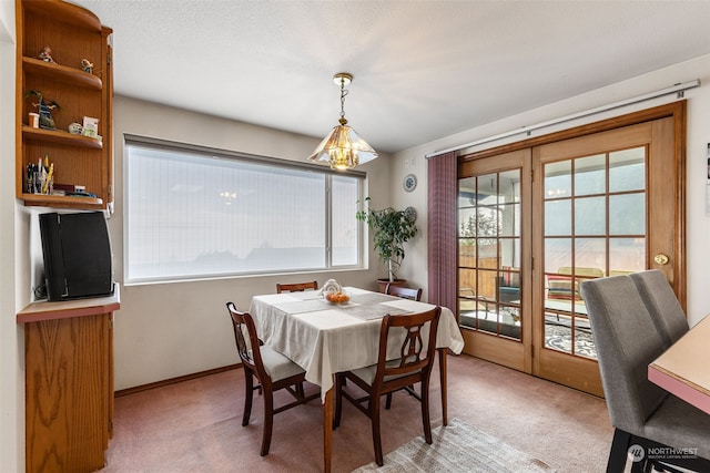 carpeted dining area with an inviting chandelier