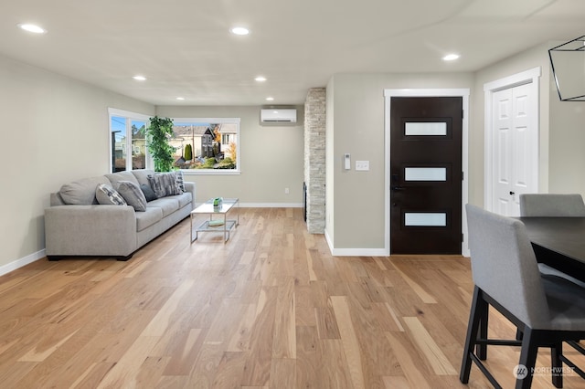 living room with an AC wall unit and light hardwood / wood-style floors