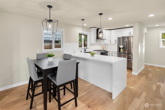 kitchen with white cabinets, stainless steel refrigerator with ice dispenser, plenty of natural light, and kitchen peninsula