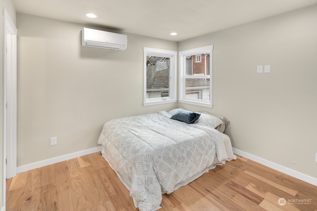 bedroom featuring a wall mounted AC and light hardwood / wood-style floors