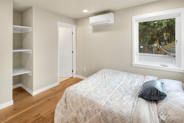 bedroom featuring light wood-type flooring and a wall mounted air conditioner